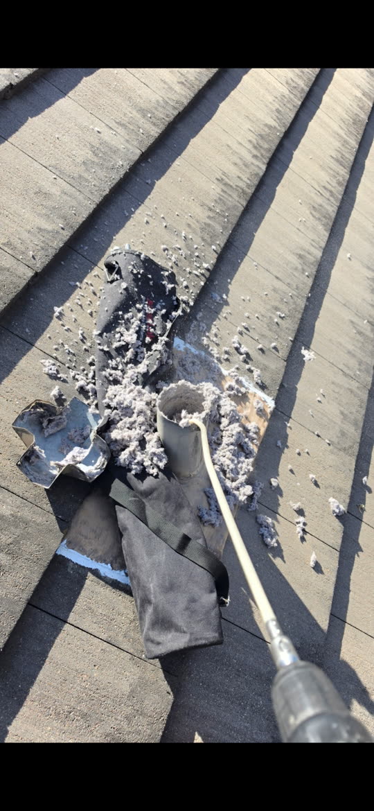 Lint piled around an opened dryer vent on a San Antonio roof after cleaning