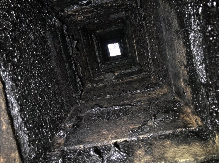 Thick black creosote buildup coating the inside of a chimney flue, a chimney fire hazard